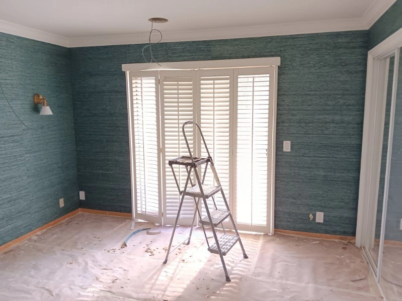 Professional wallpaper installer applying wall covering in Denver home